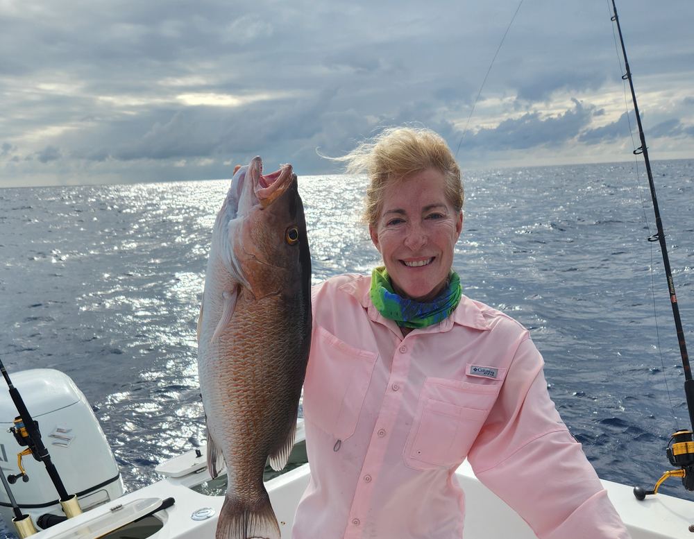 Valerie Acree offshore on her boat, holding a red snapper